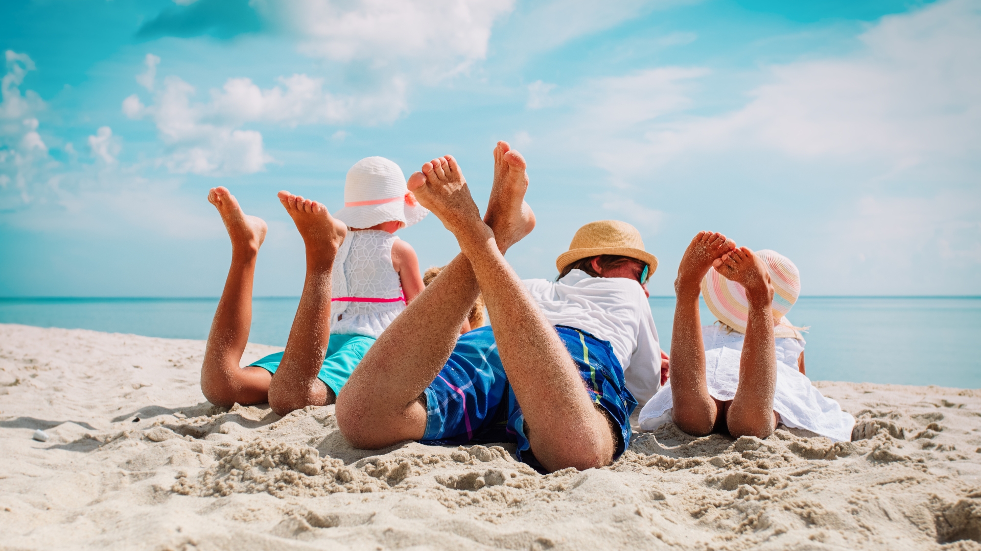 family playing in sand at a beach